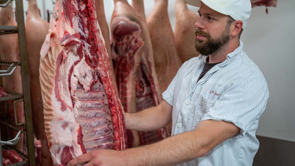 Metzger mit einer Schweinhälfte zum Zerlegen